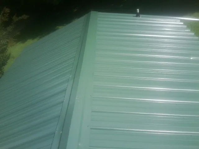 New green metal panels meeting at the ridge of a roof — Flat Roof Repair work by our crew in Cascade